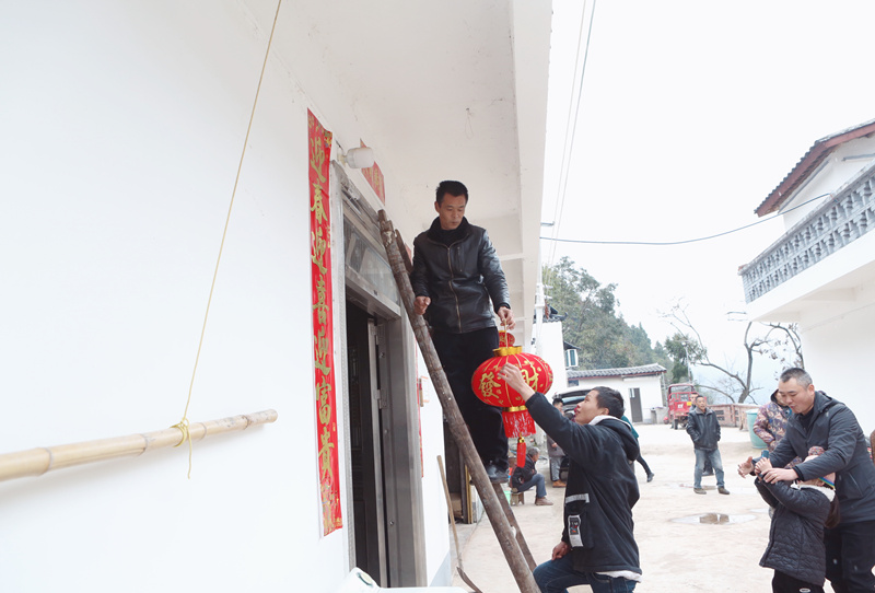 村干部為鄧厚國家掛上大紅燈籠。盧先慶攝