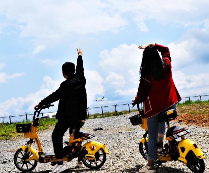 游客騎松果電單車路過機(jī)場(chǎng)時(shí)駐足觀看飛機(jī)起飛。松果出行供圖