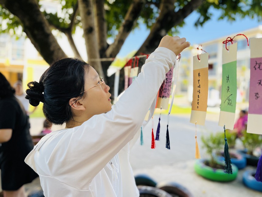 在梁平區(qū)實(shí)驗(yàn)幼兒園物流園區(qū)，家長為小朋友懸掛“愛的書簽”。