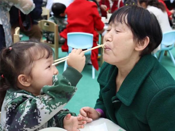 孫女正在喂奶奶吃長壽面。新絲路幼兒園供圖