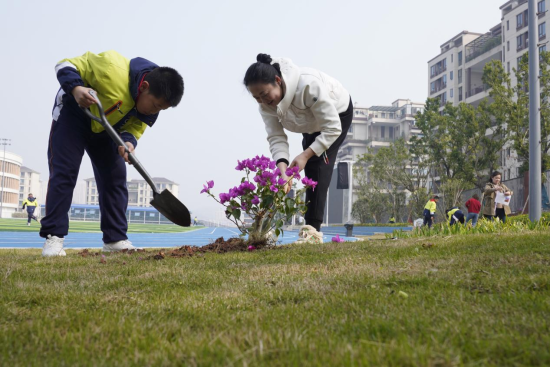 圖為學生與家長代表共同植樹現(xiàn)場。秦廷富 攝